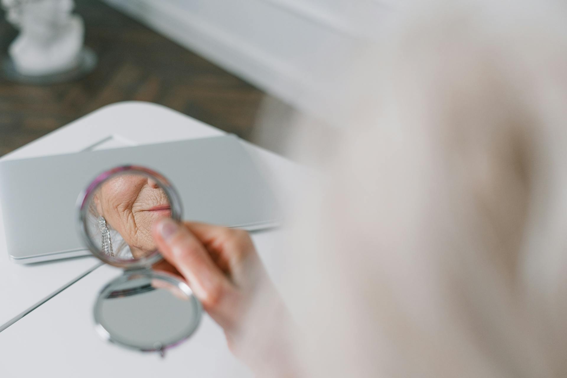 A woman with fine Line) wrinkles around her mouth looking in the mirror she's quite old