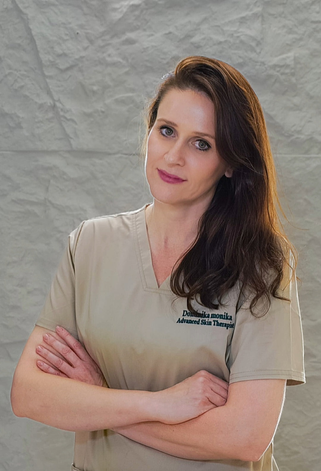 Woman wearing a beige shirt with text against a gray textured wall