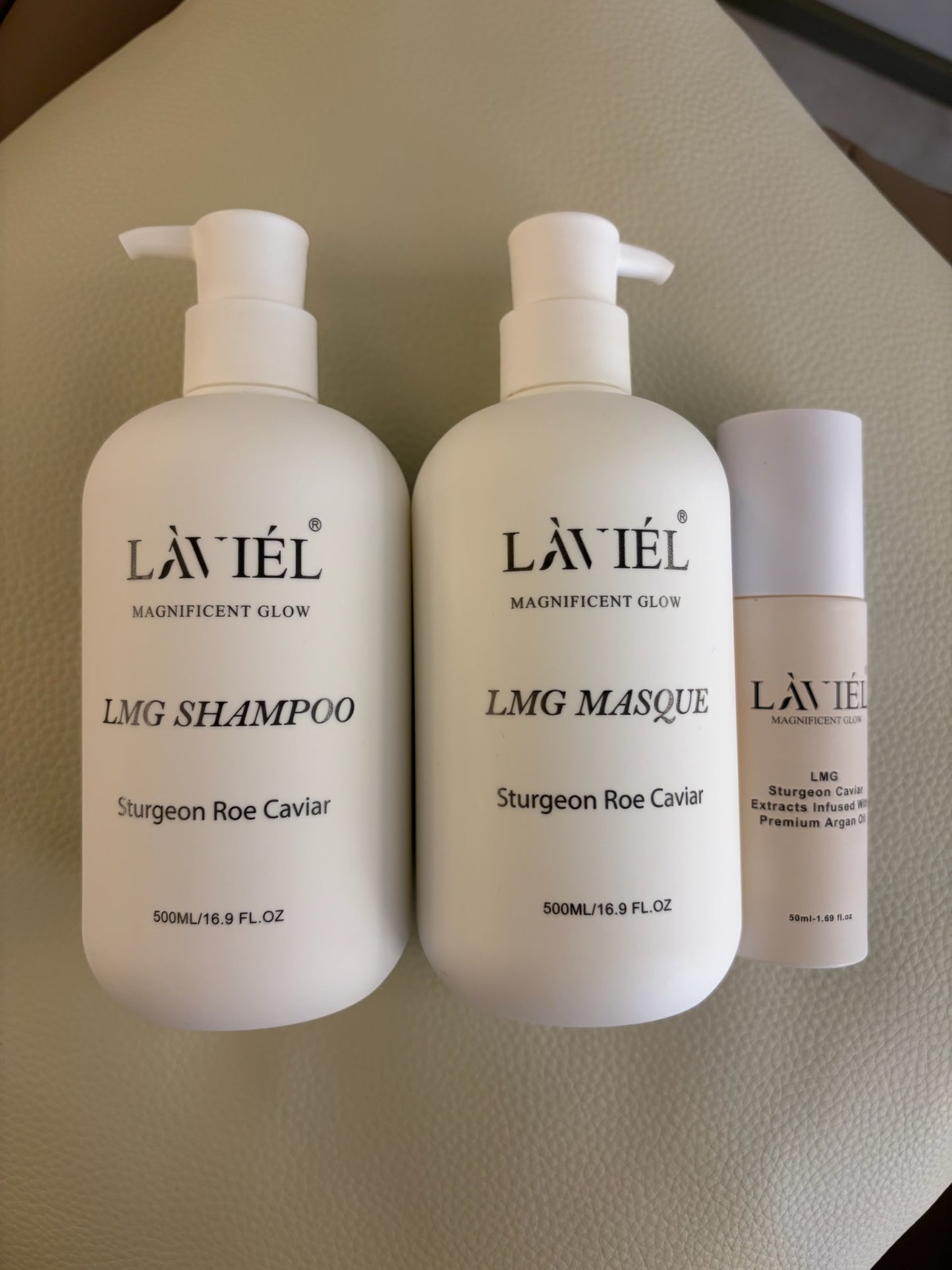 Three bottles of LAVIEIL Haircare products on a beige surface.