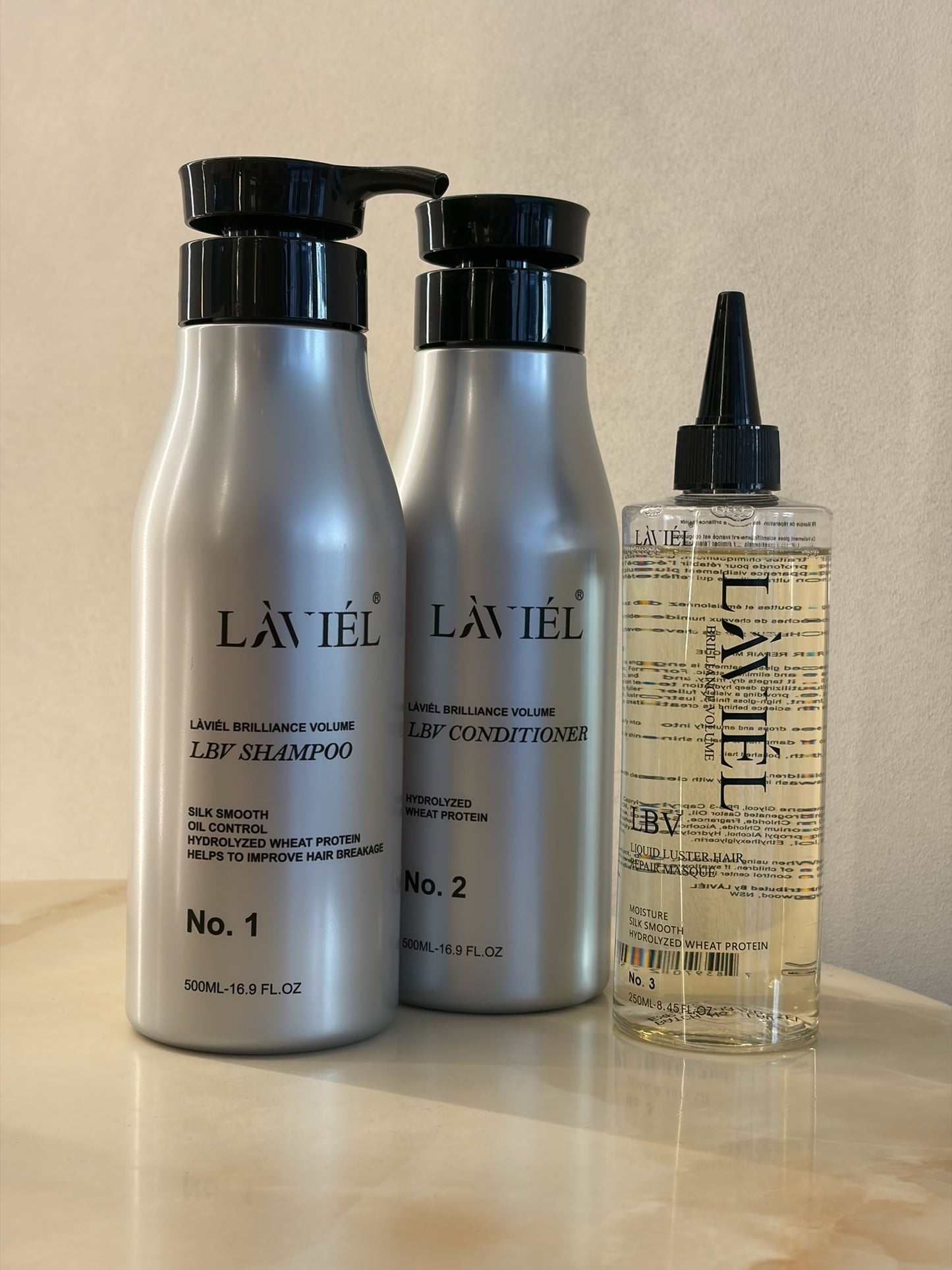 Láviél shampoo, conditioner, and hair serum bottles on a wooden surface with a neutral background.