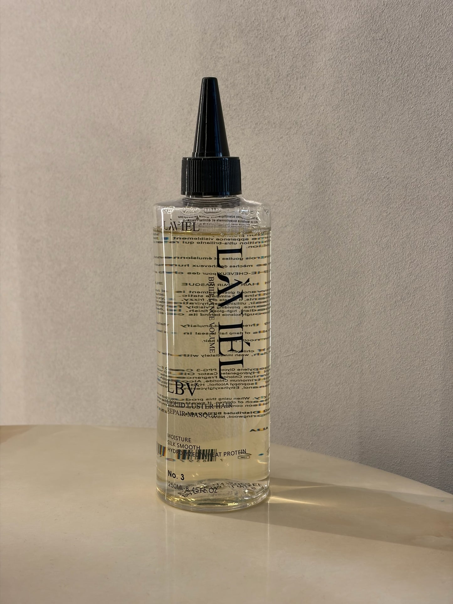 Bottle of L'AVEL hair product on a beige surface with a neutral background
