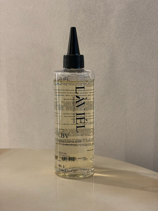 Bottle of L'AVEL hair product on a beige surface with a neutral background