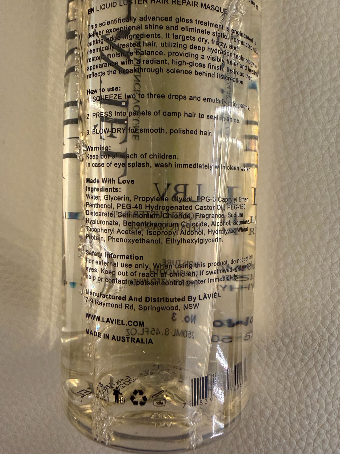 Clear bottle with text and branding on a textured beige background