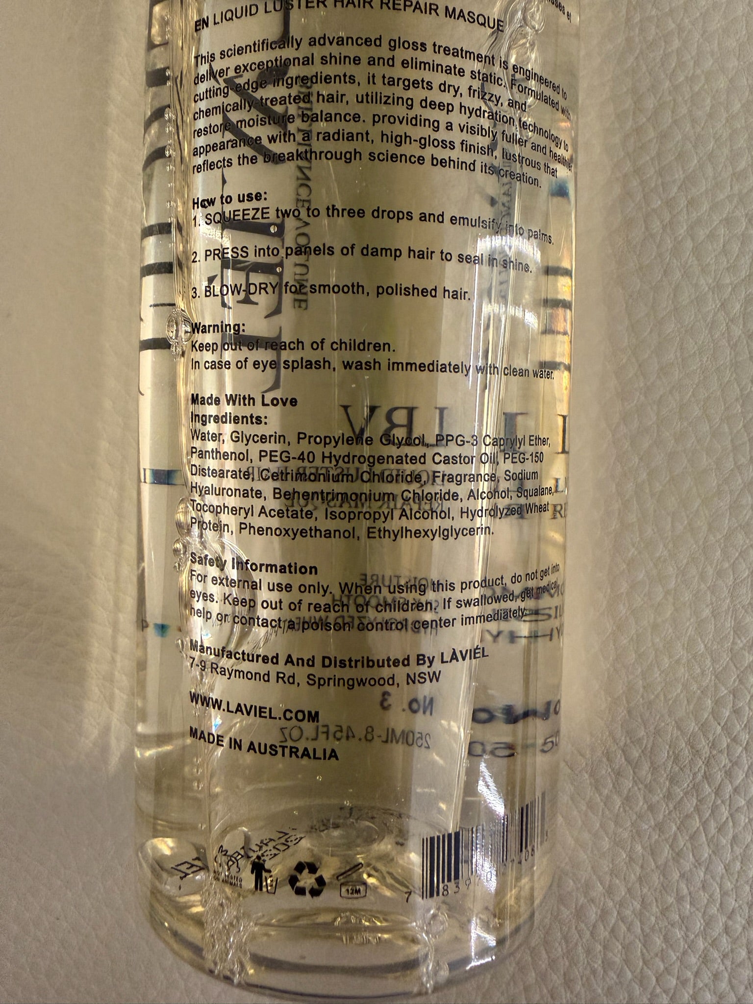 Clear bottle with text and branding on a textured beige background