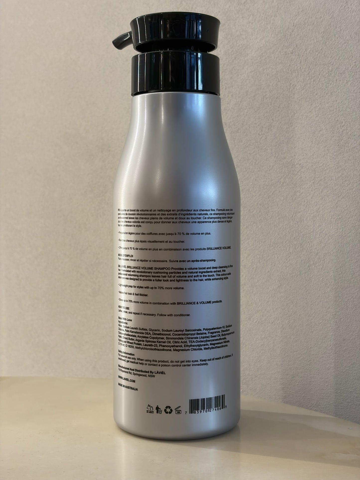 Silver bottle with black cap on a light gray background