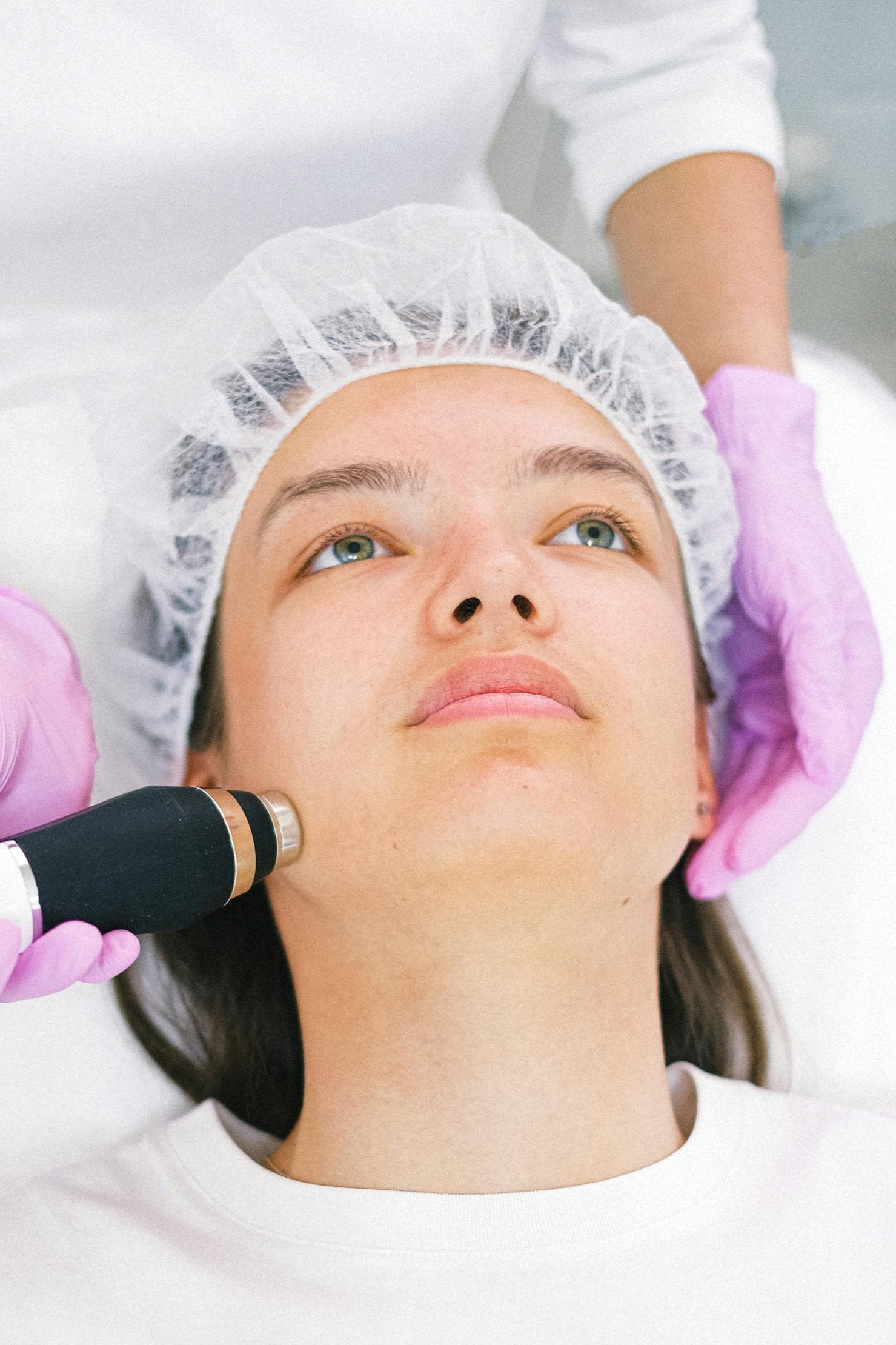 A woman with green eyes wearing a protective cap getting treatment with TMA
